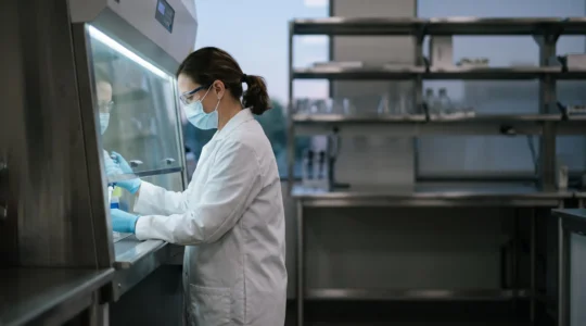 Scientifique en blouse manipulant un echantillon biologique sous un poste de securite microbiologique dans un laboratoire moderne